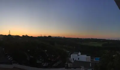 a sunset over a hill with a house and trees at Golf & Mar - T2 Apartment in Vilamoura