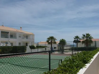 a tennis court in front of a building with palm trees at Apartamento Sunny Velamar in Patroves