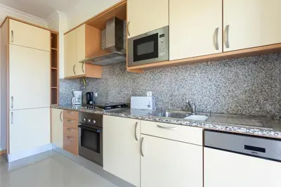 a kitchen with white cabinets and a sink at Encosta Da Orada by Garvetur in Albufeira
