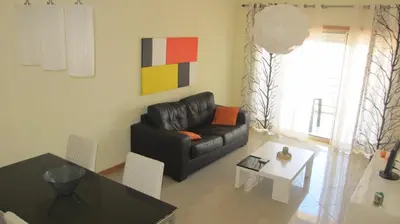 a living room with a black leather couch and a table at Encosta Da Orada by Garvetur in Albufeira