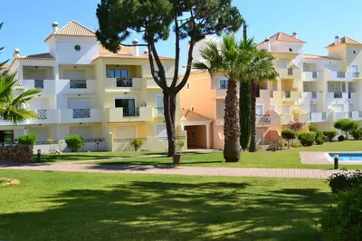 a large apartment building with palm trees in a park at Jardins Santa Eulalia by Garvetur in Albufeira
