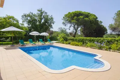 a swimming pool with chairs and umbrellas in a yard at Bonita in Quarteira