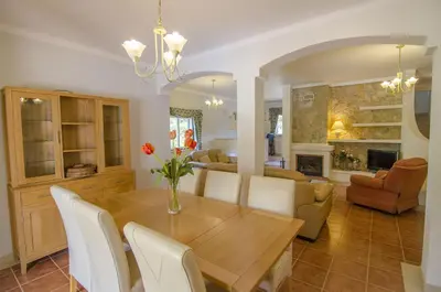 a dining room and living room with a wooden table and chairs at Bonita in Quarteira