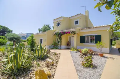 a large yellow house with plants in front of it at Bonita in Quarteira