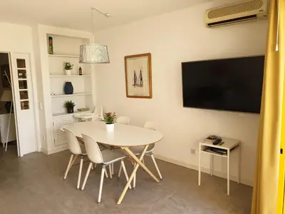 a dining room with a white table and a flat screen tv at Quinta Do Romão in Vilamoura
