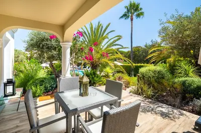 a patio with a table and chairs and palm trees at Vila Balaia - Luxury Boutique Villas in Albufeira