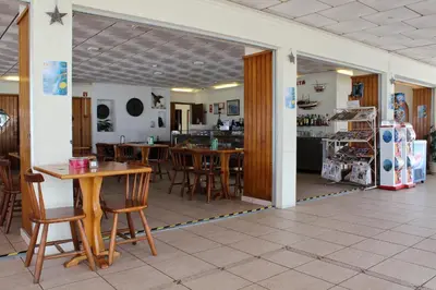 a dining room with tables and chairs and a kitchen at Aeromar Beach Hotel in Faro