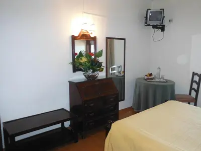 a bedroom with a dresser with a mirror and a table at Aeromar Beach Hotel in Faro