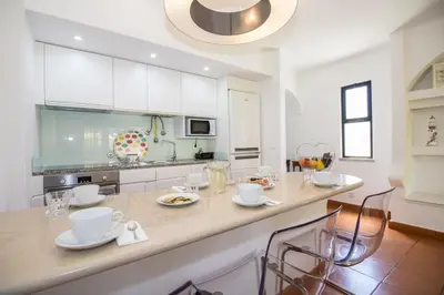 a kitchen with white cabinets and a counter with chairs at Apartamento Solar in Quarteira