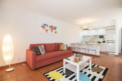 a living room with a red couch and a kitchen at Apartamento Solar in Quarteira