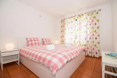 a bedroom with a bed with a red and white checkered blanket at Apartamento Solar in Quarteira
