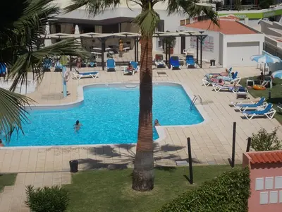 a swimming pool with a palm tree in the middle at Bellavista Apartments in Albufeira