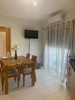 a dining room with a table and chairs and a television at Vista das Ondas - AP in Albufeira
