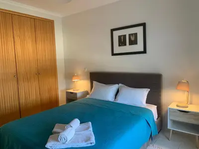 a bedroom with a blue bed with towels on it at Vista das Ondas - AP in Albufeira