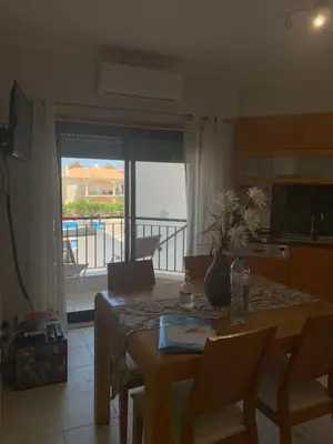 a living room with a table and a kitchen with a balcony at Vista das Ondas - AP in Albufeira