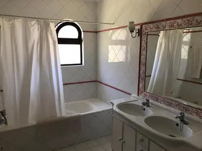 a bathroom with a sink and a tub and a mirror at Casa Camelia in Vilamoura