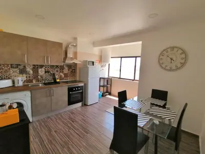 a kitchen with a table and a clock on the wall at Apartamento Penha in Faro