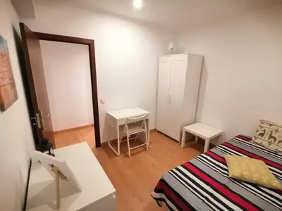 a small bedroom with a bed and a small table at Apartamento Penha in Faro