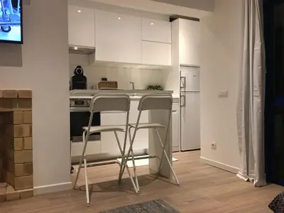 a kitchen with white cabinets and two bar stools at Apartamento Vilamoura Marina in Vilamoura