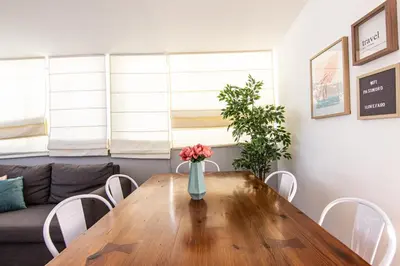 a vase of flowers on a wooden table in a living room at Faro Central - Holiday Apartments in Faro