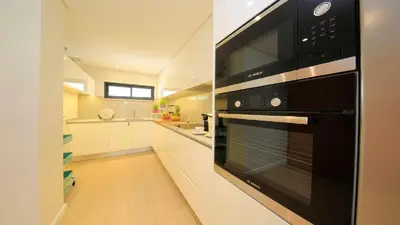 a kitchen with a black oven and white cabinets at NOA Apartment Quinta do Lago in Quinta do Lago