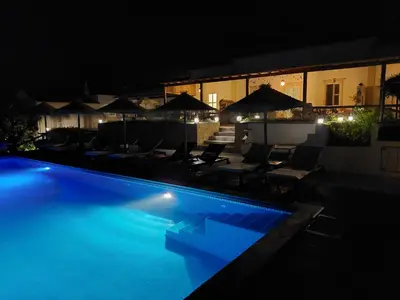 a swimming pool at night with chairs and umbrellas at Retiro da Janela in Boliqueime