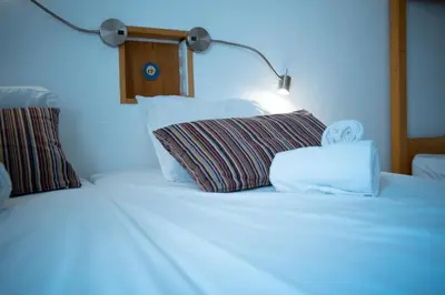 a bed with two pillows and a lamp on it at Wax Hostel in Faro