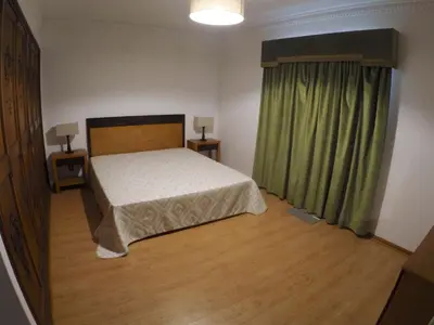 a bedroom with a bed and a window with green curtains at Vila Ninita in Vilamoura