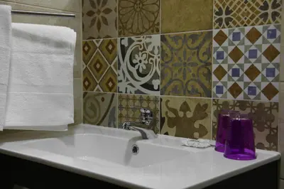 a bathroom sink with a purple bottle and towels at Happy House in Faro