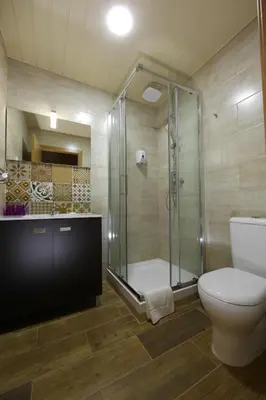 a bathroom with a glass shower and a toilet at Happy House in Faro