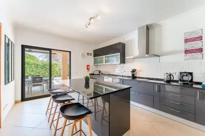 a kitchen with a counter and stools in it at Casa no Sol in Loulé