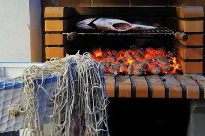 a fire in an oven with some food in it at 3 Villas - Praia da Falesia in Albufeira