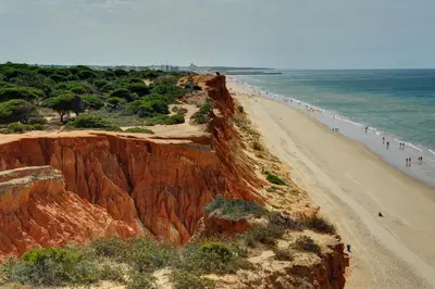 a beach with people walking on the sand and the ocean at 3 Villas - Praia da Falesia in Albufeira
