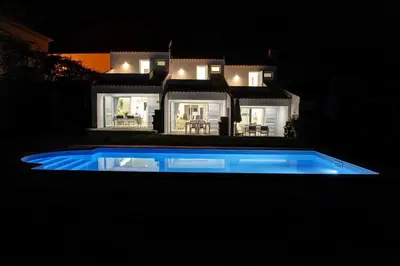 a swimming pool in front of a house at night at 3 Villas - Praia da Falesia in Albufeira