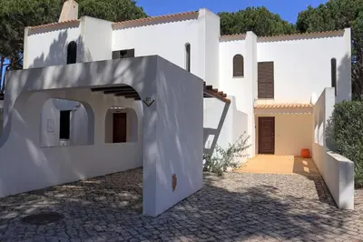 a white house with an archway in front of it at Villa V2 Duplex - Vilamoura Tennis in Quarteira