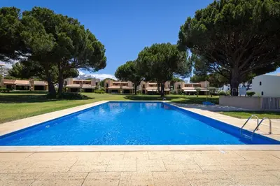 a swimming pool with trees and houses in the background at Villa V2 Duplex - Vilamoura Tennis in Quarteira