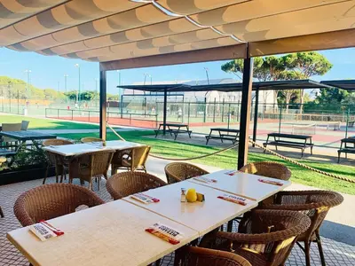 a row of tables and chairs with a tennis court at Villa V2 Duplex - Vilamoura Tennis in Quarteira