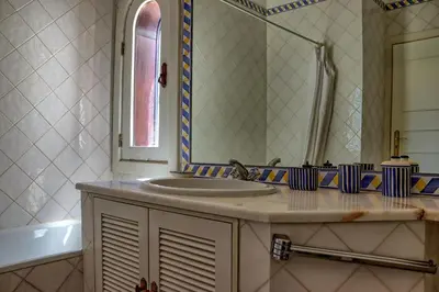 a bathroom with a sink and a mirror and a tub at Villa V2 Duplex - Vilamoura Tennis in Quarteira