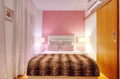 a bedroom with a large bed with pink walls at Casa da Avó in Faro