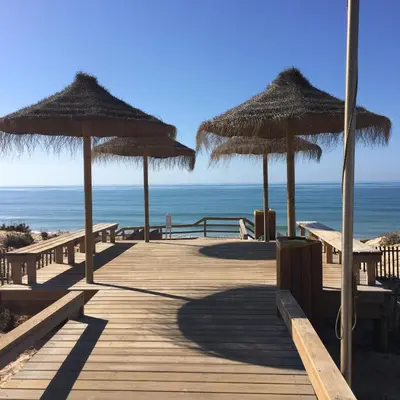 a wooden boardwalk with straw umbrellas on the beach at Apartment in Algarve,Vilamoura in Vilamoura
