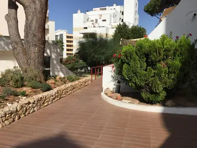 a walkway with a tree and some bushes and buildings at Apartment in Algarve,Vilamoura in Vilamoura