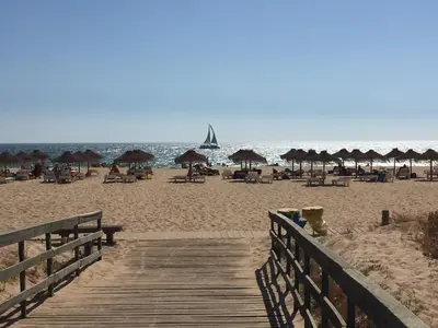 a wooden boardwalk leading to a beach with umbrellas at Apartment in Algarve,Vilamoura in Vilamoura