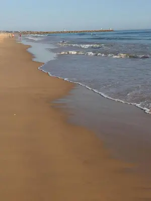 a beach with the ocean and people walking on it at Apartment in Algarve,Vilamoura in Vilamoura
