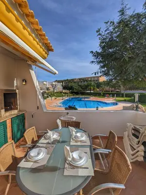 a patio with a table and chairs and a swimming pool at Townhouse 700m from Sao Rafael Beach in Albufeira
