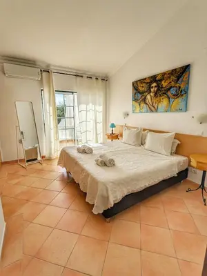 a bedroom with a large bed and a painting on the wall at Townhouse 700m from Sao Rafael Beach in Albufeira