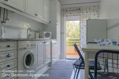 a kitchen with a washer and dryer and a table at Akisol Vilamoura Sun III in Vilamoura