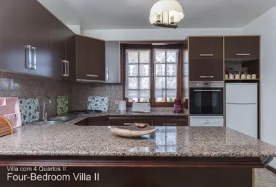 a kitchen with brown cabinets and a granite counter top at Akivillas Quarteira Rose in Quarteira