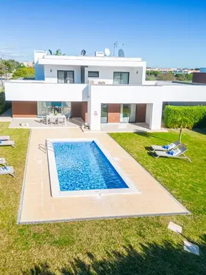 a villa with a swimming pool in front of a house at Villas Novochoro - Large Garden- Heatable Pool by DreamvillasAlbufeira in Albufeira