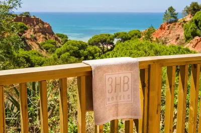 a towel on a wooden railing with a big sign on it at 3HB Falésia Garden in Albufeira