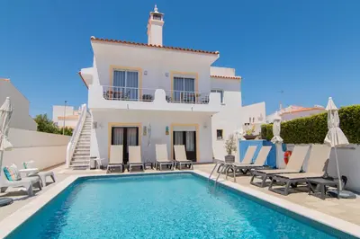 a villa with a swimming pool in front of a house at Apartments Salomé in Albufeira